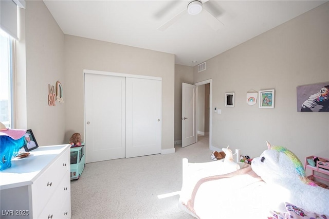 bedroom with visible vents, a ceiling fan, a closet, and light carpet