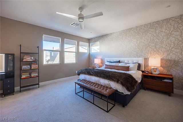 carpeted bedroom featuring wallpapered walls, baseboards, a ceiling fan, and visible vents