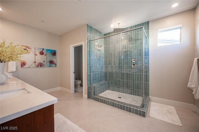 bathroom with tile patterned flooring, toilet, a sink, a stall shower, and baseboards