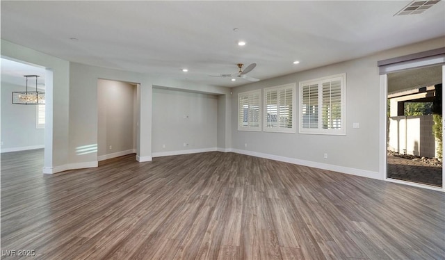 unfurnished room featuring a healthy amount of sunlight, baseboards, dark wood-style floors, and visible vents