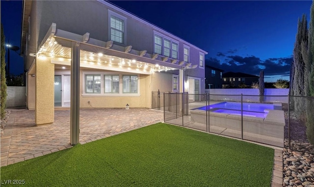 back of house at night with a pergola, a patio area, fence, stucco siding, and a fenced in pool
