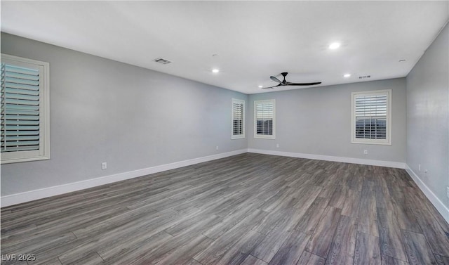 spare room with visible vents, baseboards, a ceiling fan, and dark wood finished floors