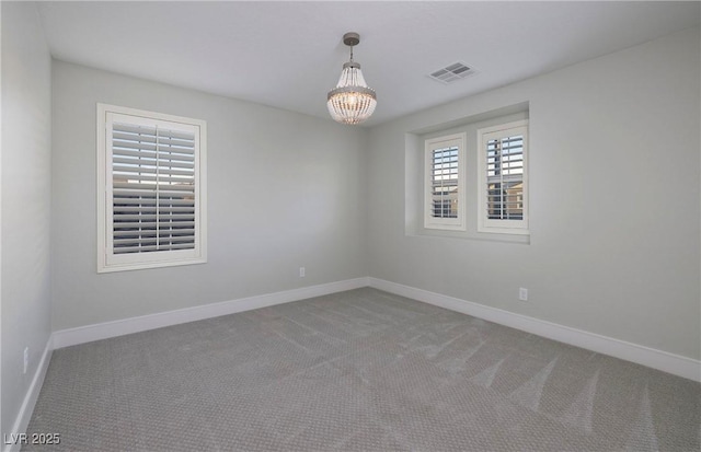 carpeted spare room featuring visible vents, baseboards, and an inviting chandelier