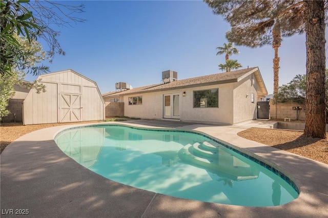 rear view of property with central air condition unit, fence, an outdoor structure, a shed, and a fenced in pool