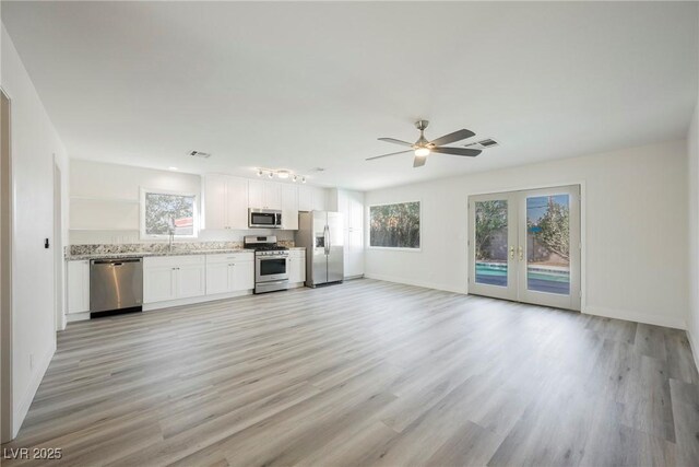 interior space with a wealth of natural light, appliances with stainless steel finishes, visible vents, and white cabinetry
