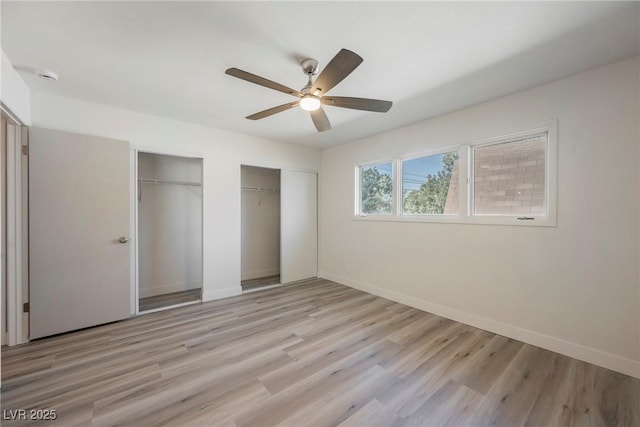 unfurnished bedroom with light wood finished floors, baseboards, ceiling fan, and multiple closets