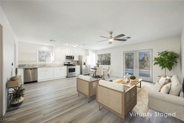 living area featuring a ceiling fan, french doors, visible vents, and plenty of natural light