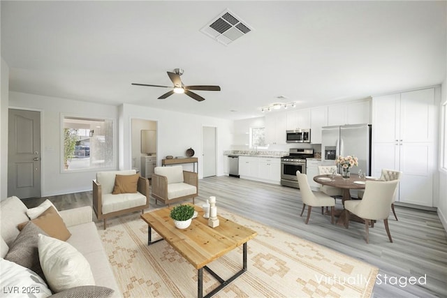 living room with a healthy amount of sunlight, ceiling fan, light wood-type flooring, and visible vents