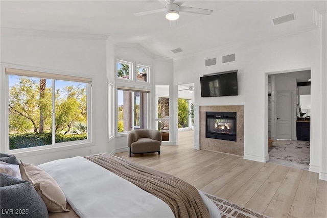 bedroom with wood finished floors, a multi sided fireplace, visible vents, baseboards, and ornamental molding
