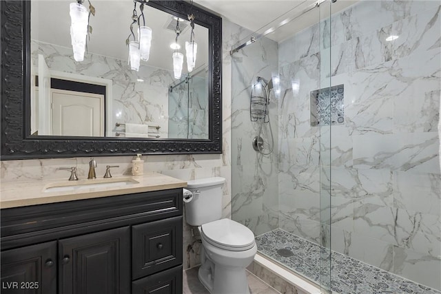 full bathroom featuring tile walls, toilet, vanity, a marble finish shower, and a chandelier