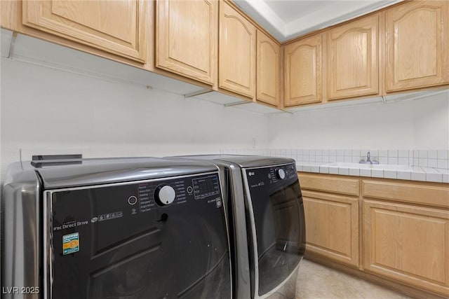 clothes washing area featuring washing machine and dryer, a sink, cabinet space, and light tile patterned floors
