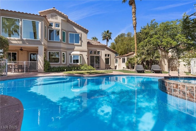 view of swimming pool featuring a pool with connected hot tub, fence, and ceiling fan