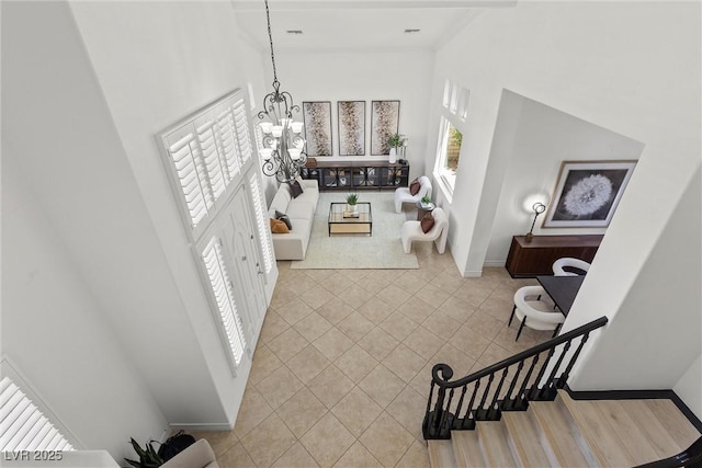 foyer featuring a high ceiling, baseboards, a notable chandelier, and tile patterned floors