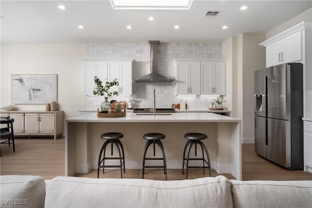 1624 Preston Park Dr, Henderson, NV 89052 - kitchen featuring stainless steel fridge with ice dispenser, wall chimney range hood, a sink, a kitchen bar, and backsplash