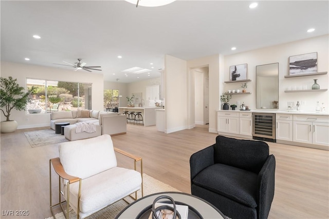 living area with beverage cooler, bar area, recessed lighting, a ceiling fan, and light wood-type flooring