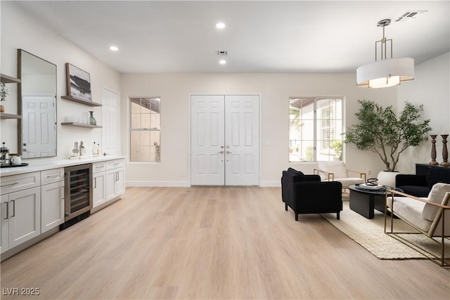 indoor wet bar featuring beverage cooler, light wood-style flooring, hanging light fixtures, recessed lighting, and baseboards