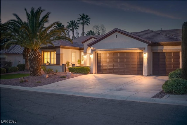 view of front facade featuring stucco siding, an attached garage, driveway, and a tile roof