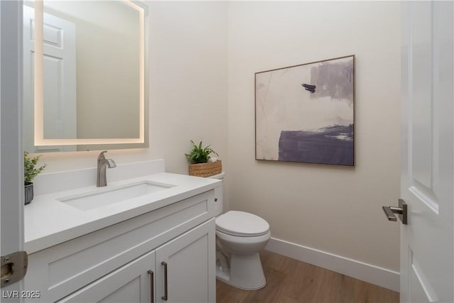 bathroom featuring vanity, wood finished floors, toilet, and baseboards