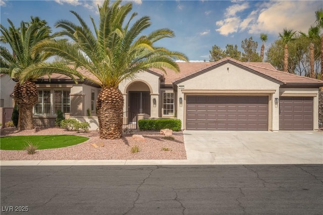 mediterranean / spanish-style house with a garage, concrete driveway, stucco siding, and a tile roof