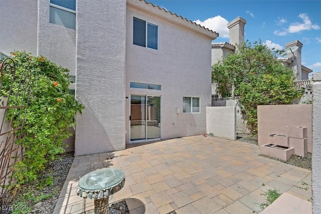 back of property with a patio area, a chimney, a tile roof, fence, and stucco siding