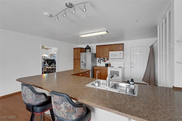 1800 Red Rock Dr, Pahrump, NV 89048 - kitchen featuring a kitchen breakfast bar, white appliances, brown cabinets, a sink, and wood finished floors