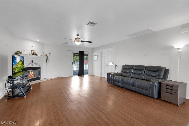 1800 Red Rock Dr, Pahrump, NV 89048 - living area with a glass covered fireplace, visible vents, ceiling fan, and wood finished floors