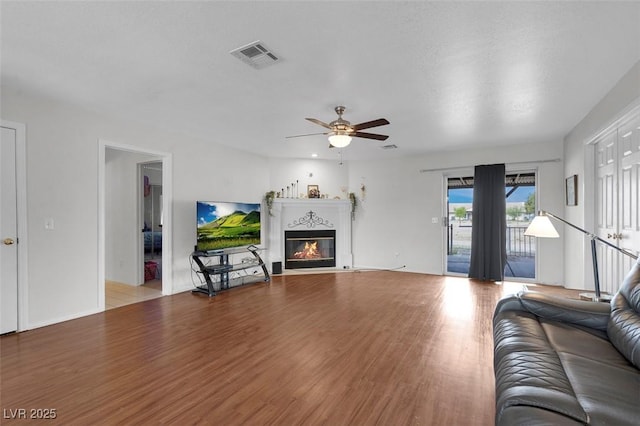 1800 Red Rock Dr, Pahrump, NV 89048 - living room with wood finished floors, ceiling fan, a glass covered fireplace, and visible vents