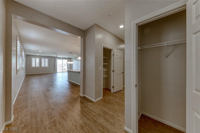 corridor featuring wood finished floors, baseboards, and recessed lighting