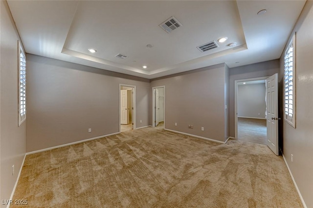 unfurnished room with carpet, visible vents, and a raised ceiling