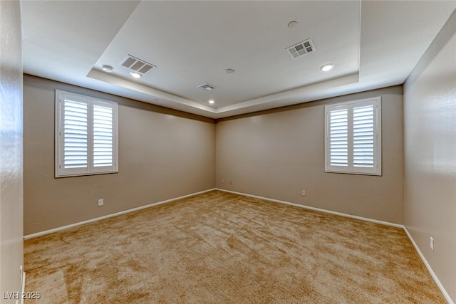 carpeted empty room with a tray ceiling, plenty of natural light, baseboards, and recessed lighting