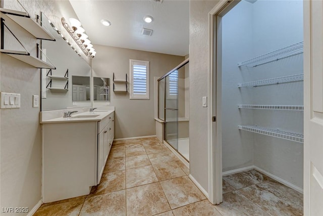 full bathroom featuring a stall shower, double vanity, tile patterned floors, and baseboards
