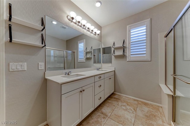 bathroom featuring a shower stall, healthy amount of natural light, double vanity, and baseboards