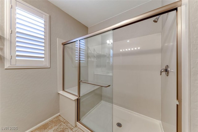 bathroom with a stall shower and baseboards