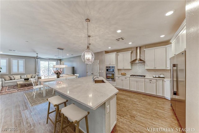 2767 Flowing Breeze St, Henderson, NV 89044 - kitchen with wall chimney exhaust hood, gas cooktop, a sink, open floor plan, and white cabinetry