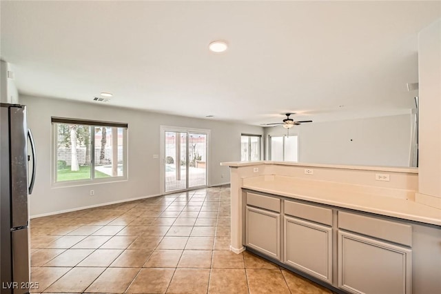 7829 Lovely Pine Pl, Las Vegas, NV 89143 - kitchen with light tile patterned floors, open floor plan, a ceiling fan, freestanding refrigerator, and a peninsula