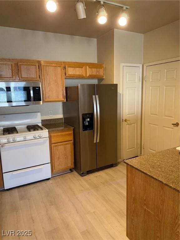 kitchen featuring appliances with stainless steel finishes, light wood finished floors, and dark countertops