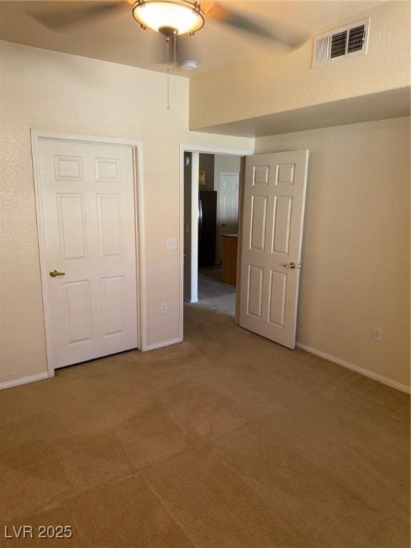 carpeted empty room featuring visible vents, baseboards, and ceiling fan