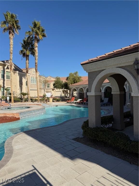pool with a patio and a hot tub