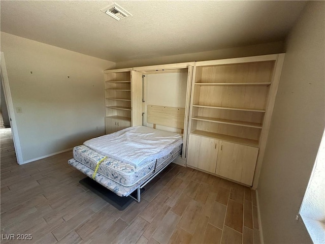 9048 Litchfield Ave, Las Vegas, NV 89134 - bedroom featuring a textured ceiling, baseboards, visible vents, and wood finished floors