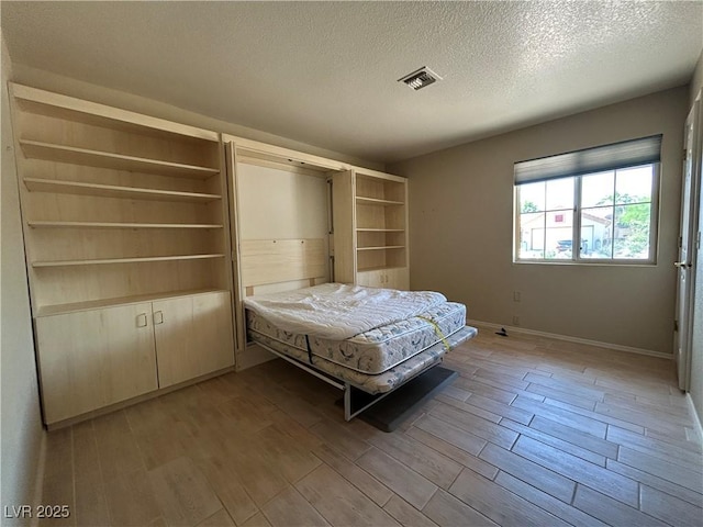 9048 Litchfield Ave, Las Vegas, NV 89134 - bedroom featuring visible vents, a textured ceiling, baseboards, and wood finish floors