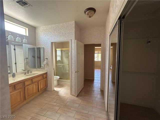 9048 Litchfield Ave, Las Vegas, NV 89134 - bathroom with vanity, toilet, a textured ceiling, visible vents, and a stall shower