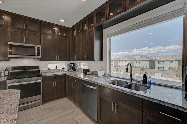 7953 Mountain Lilac St, Las Vegas, NV 89113 - kitchen featuring light wood-type flooring, dark brown cabinets, light stone countertops, stainless steel appliances, and a sink