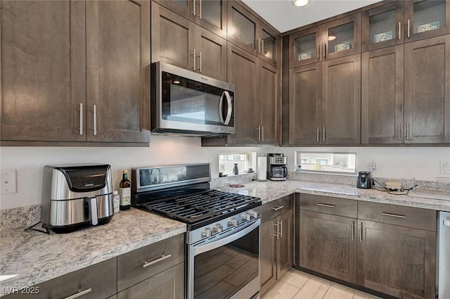 7953 Mountain Lilac St, Las Vegas, NV 89113 - kitchen with stainless steel appliances, glass insert cabinets, light stone counters, and dark brown cabinets