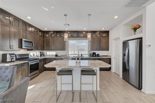 7953 Mountain Lilac St, Las Vegas, NV 89113 - kitchen with appliances with stainless steel finishes, wood finish floors, dark brown cabinets, and visible vents