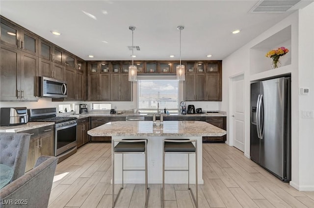 7953 Mountain Lilac St, Las Vegas, NV 89113 - kitchen with dark brown cabinetry, visible vents, wood tiled floor, and appliances with stainless steel finishes