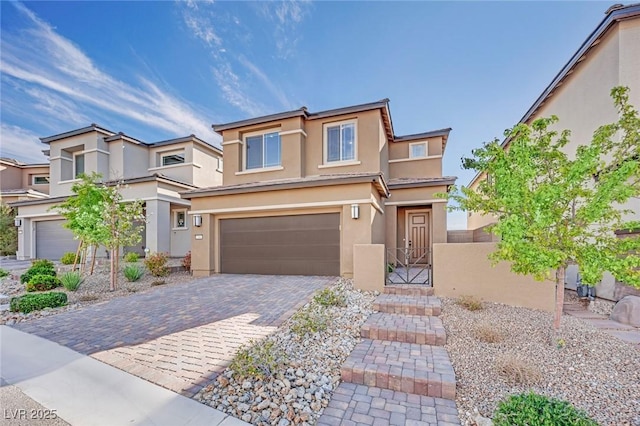 view of front of house featuring a gate, stucco siding, an attached garage, and decorative driveway