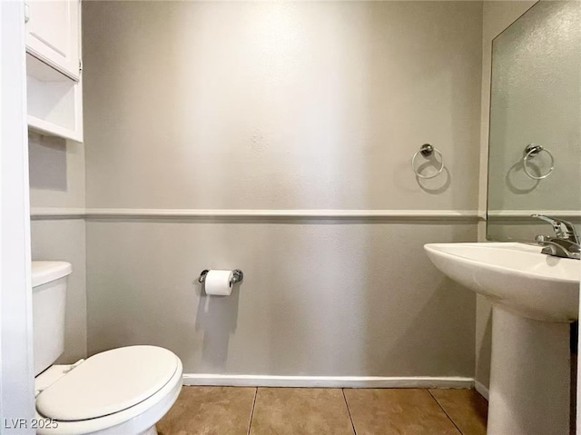 bathroom with toilet, a sink, baseboards, and tile patterned flooring