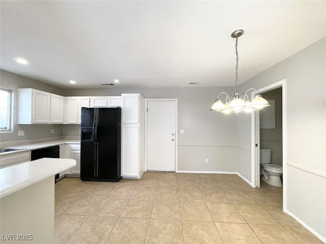 kitchen with light tile patterned floors, light countertops, white cabinets, decorative light fixtures, and black appliances