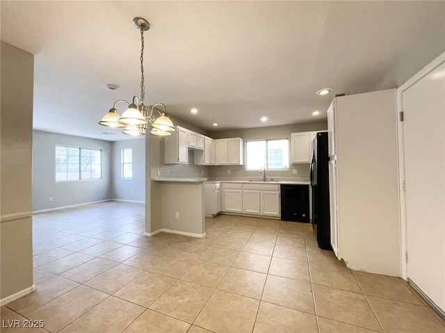 kitchen featuring an inviting chandelier, light tile patterned flooring, a wealth of natural light, black appliances, and a sink