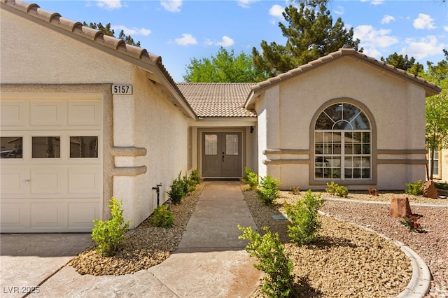 property entrance with an attached garage, a tiled roof, and stucco siding